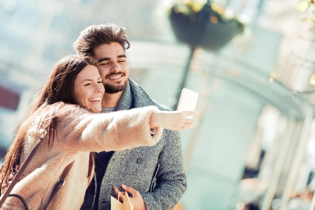 Heureux jeune couple dans la ville prenant selfie