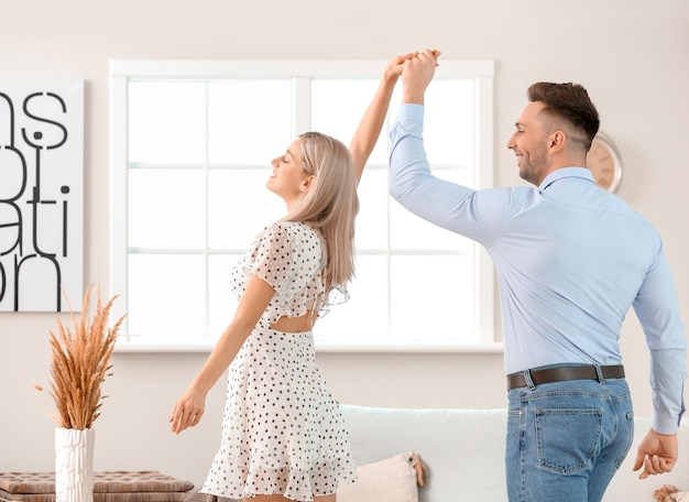 Heureux jeune couple dansant à la maison