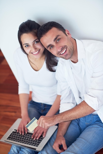 heureux jeune couple détendu travaillant sur un ordinateur portable à l'intérieur de la maison moderne