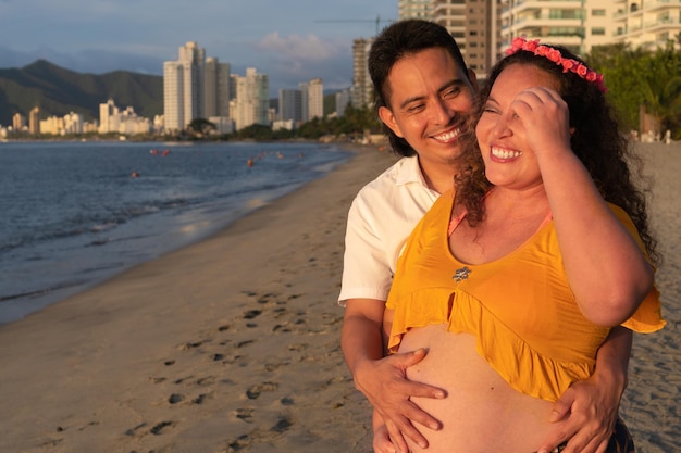 Heureux jeune couple enceinte relaxant sur la plage