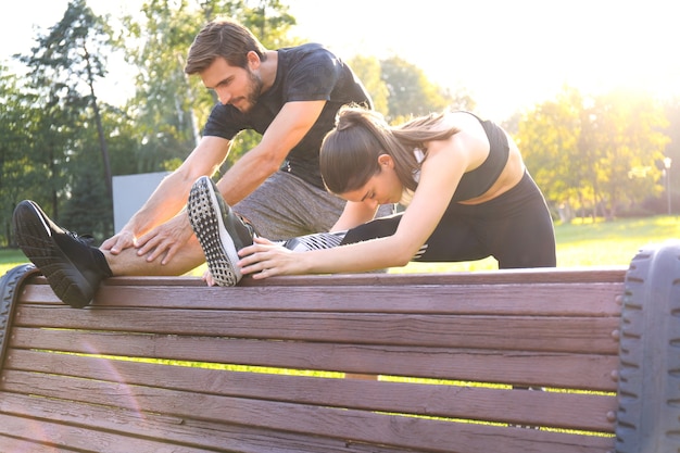 Heureux jeune couple exerçant ensemble dans un parc, exercices d'étirement.