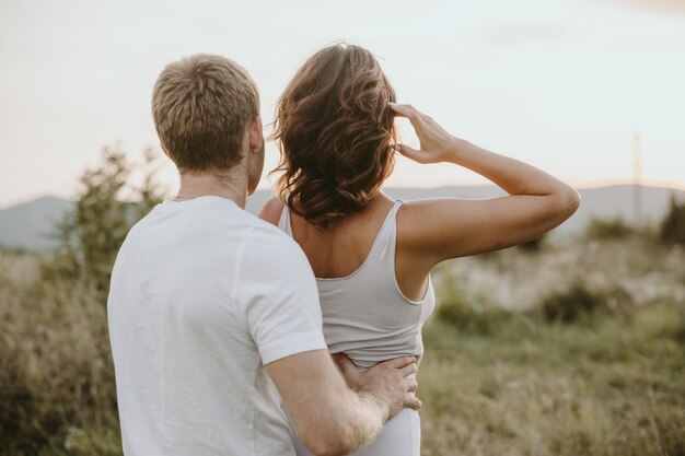 Heureux jeune couple sur fond de nature. Fille montrant avec la main. Notion d'amour