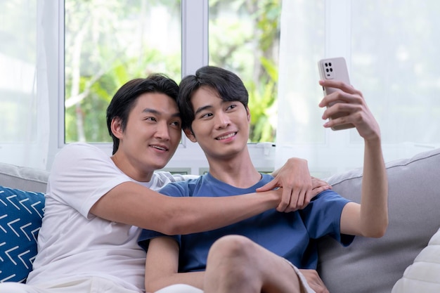 Heureux jeune couple gay asiatique prenant selfie dans le salon Concept de style de vie de couple LGBT