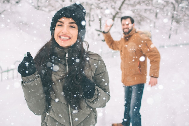 Heureux jeune couple en hiver. Famille à l'extérieur. homme et femme regardant vers le haut et riant. Amour, plaisir, saison et gens - marcher dans le parc d'hiver. Il fait boule de neige
