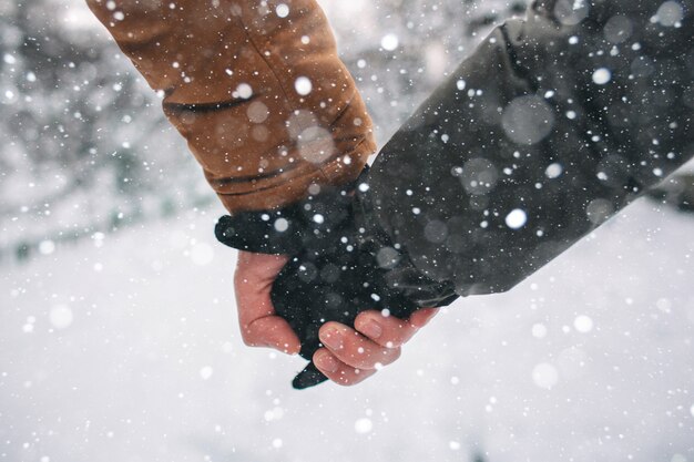 Heureux jeune couple en hiver. Famille à l'extérieur. homme et femme regardant vers le haut et riant. Amour, plaisir, saison et gens - marcher dans le parc d'hiver. Tenant la main, gros plan.