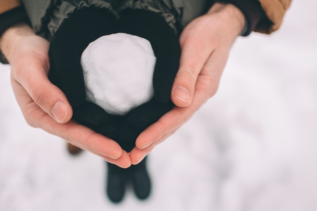 Heureux jeune couple en hiver. Famille en plein air. homme et femme regardant vers le haut et en riant. Amour, amusement, saisons et gens - promenade dans le parc d'hiver. Boule de neige dans les mains du gros plan.