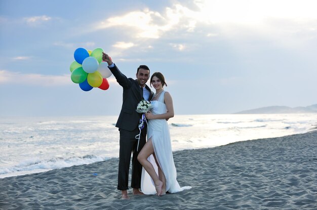 heureux jeune couple juste marié célébrant et s'amusant au magnifique coucher de soleil sur la plage