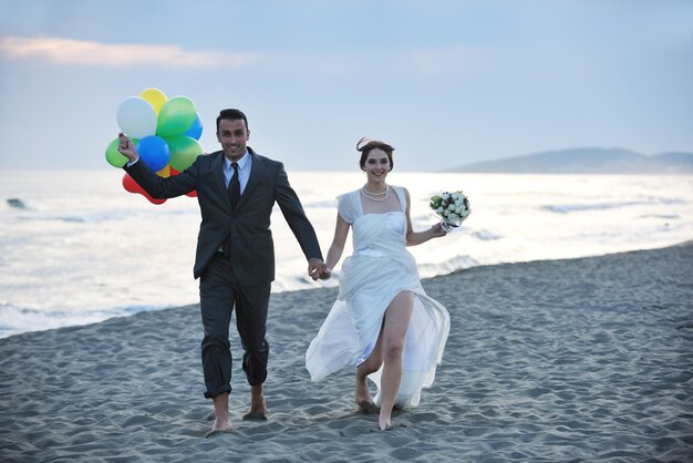 heureux jeune couple juste marié célébrant et s'amusant au magnifique coucher de soleil sur la plage