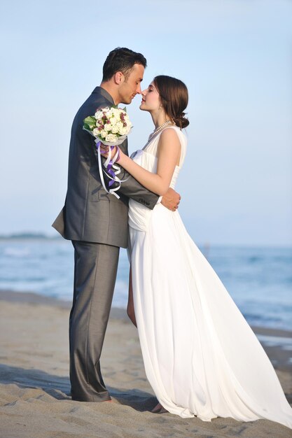 heureux jeune couple juste marié célébrant et s'amusant au magnifique coucher de soleil sur la plage