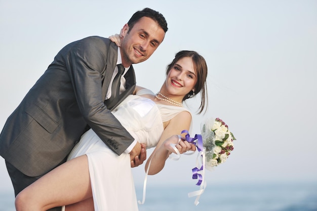 heureux jeune couple juste marié célébrant et s'amusant au magnifique coucher de soleil sur la plage