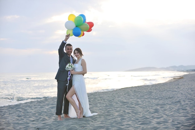 heureux jeune couple juste marié célébrant et s'amusant au magnifique coucher de soleil sur la plage