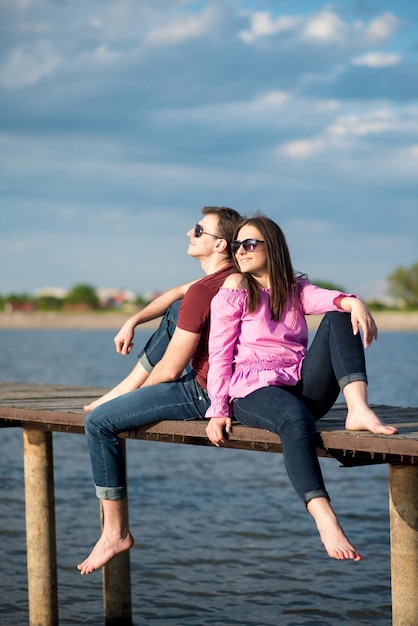 Heureux jeune couple marchant sur la jetée sur le lac par une journée d'été ensoleillée