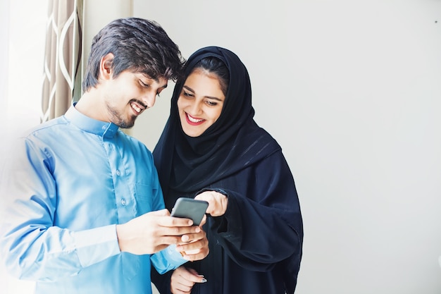 Heureux Jeune Couple Musulman Utilisant L'application Sur Téléphone Mobile