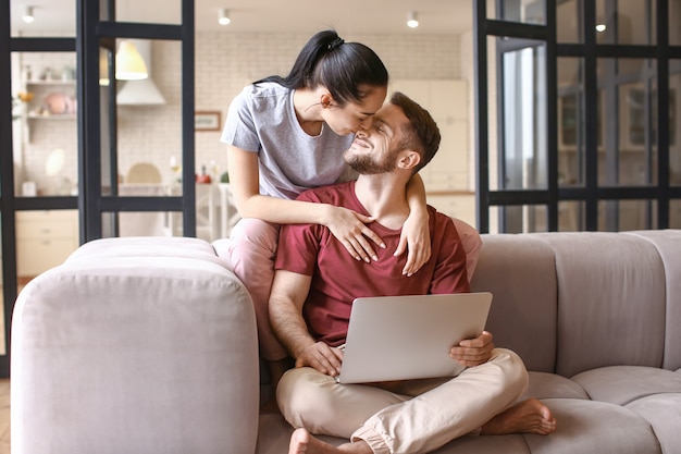 Heureux jeune couple avec ordinateur portable à la maison