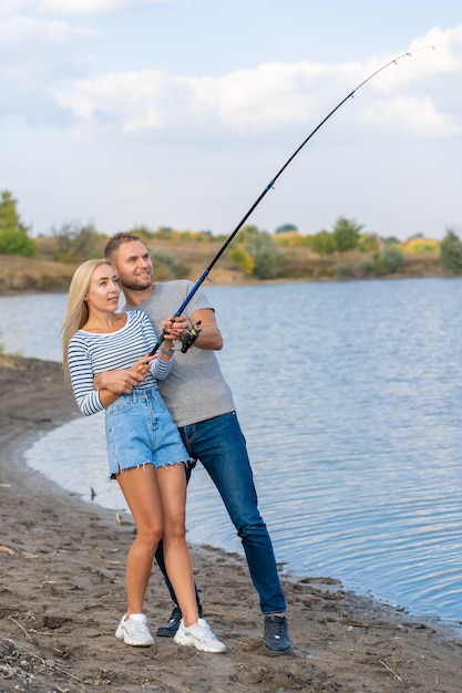 Heureux jeune couple pêchant au bord du lac