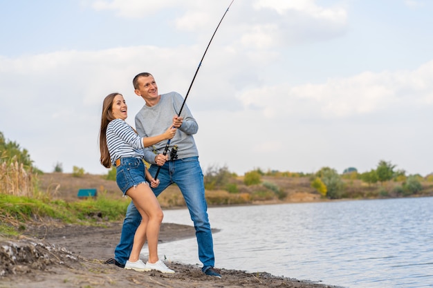 Heureux jeune couple pêchant au bord du lac