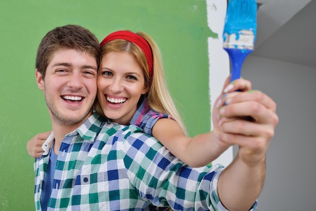 heureux jeune couple peint en vert et bleu le mur blanc de leur nouvelle maison