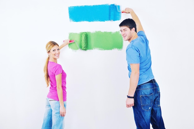 heureux jeune couple peint en vert et bleu le mur blanc de leur nouvelle maison