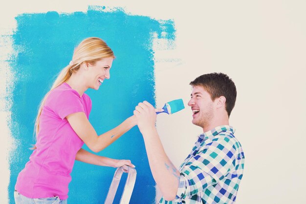 heureux jeune couple peint en vert et bleu le mur blanc de leur nouvelle maison