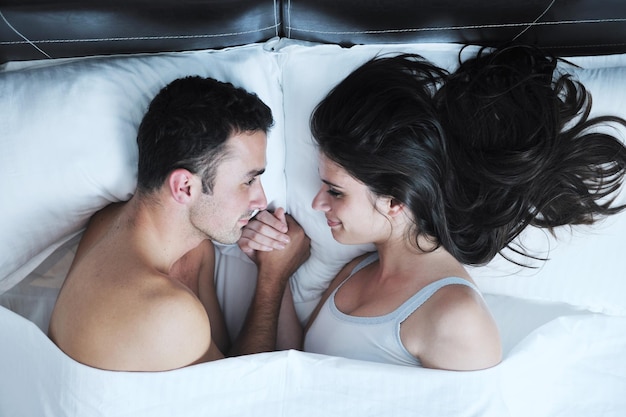 heureux jeune couple de personnes en bonne santé passe du bon temps dans leur chambre à coucher faire l'amour et dormir