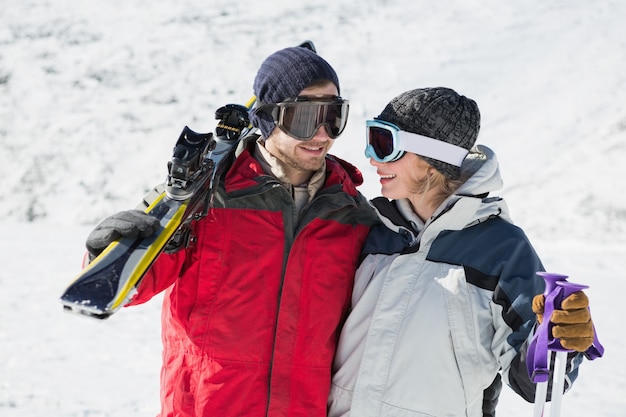 Photo heureux jeune couple avec des planches de ski sur la neige