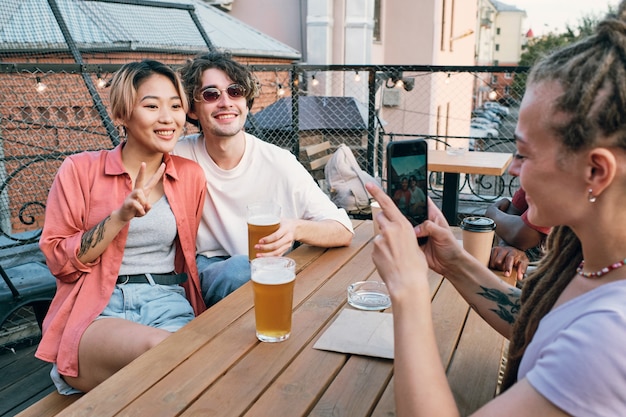 Heureux jeune couple posant pour leur ami avec smartphone