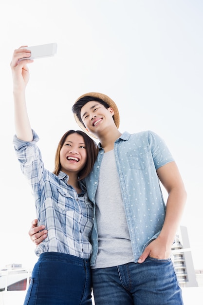 Heureux jeune couple prenant un selfie sur l'extérieur du smartphone