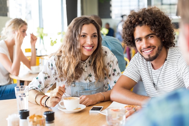 Heureux jeune couple prenant son petit déjeuner dans une cafétéria avec un ami