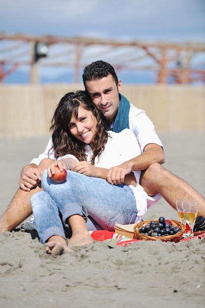 heureux jeune couple profitant d'un pique-nique sur la plage et passer du bon temps pendant les vacances d'été