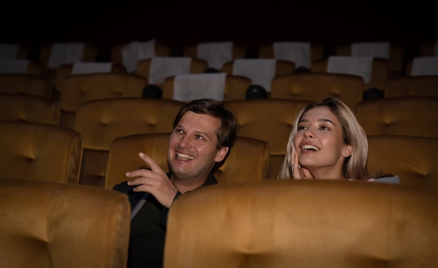 Heureux jeune couple regardant le film au cinéma