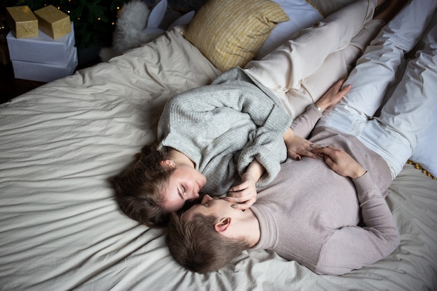 Heureux jeune couple restant au lit à la maison