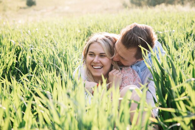 Heureux jeune couple rêvant et s'amusant ensemble dans le champ sur l'herbe