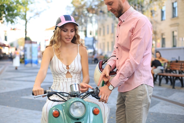 Heureux jeune couple riding scooter en ville. Beau mec et jeune femme voyagent. Concept d'aventure et de vacances.