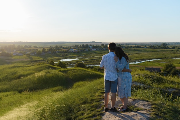 Heureux jeune couple s'embrassant au sommet d'une montagne, avec un ciel clair. Famille heureuse