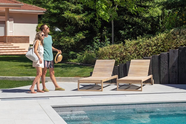 Heureux jeune couple s'embrassant à la piscine par une chaude journée d'été dans leur jardin