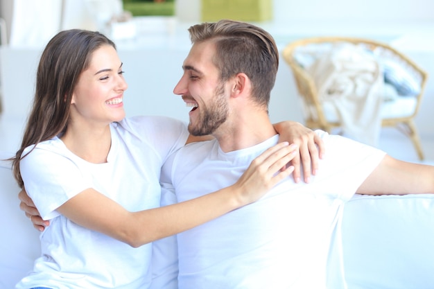 Heureux jeune couple s'embrassant et se regardant à l'intérieur de la maison.