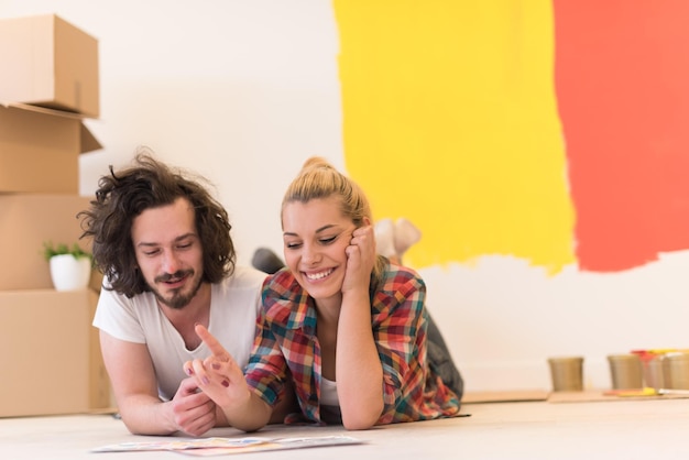 Heureux jeune couple se détendre après avoir peint une pièce dans leur nouvelle maison sur le sol