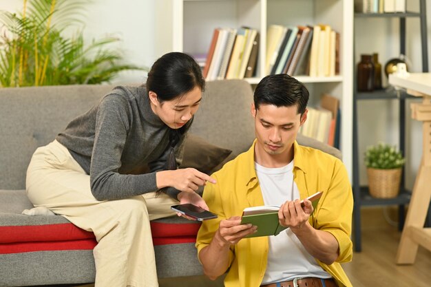 Heureux jeune couple se détendre en lisant un livre en profitant du temps libre le week-end à la maison