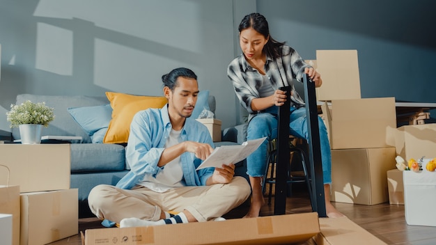 Heureux jeune couple séduisant asiatique homme et femme s'entraident dans la boîte de déballage et assemblent des meubles