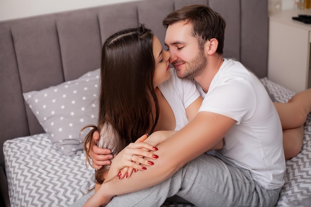 Heureux jeune couple sensuel couché dans son lit ensemble