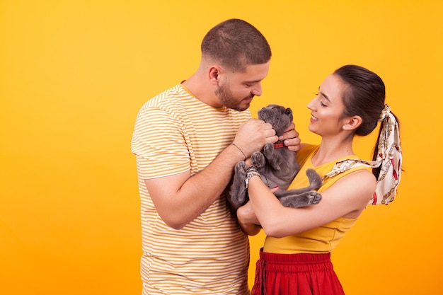 Heureux jeune couple souriant et jouant avec leur chat. Chat regardant le propriétaire.