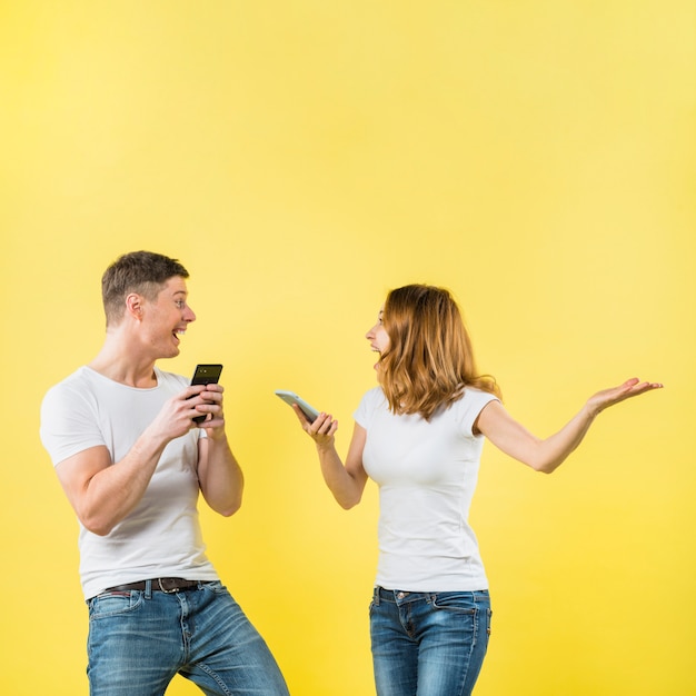 Heureux jeune couple tenant un téléphone portable dans la main en criant de joie