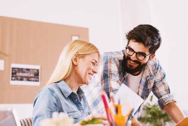 Heureux jeune couple travaillant ensemble dans le même bureau.