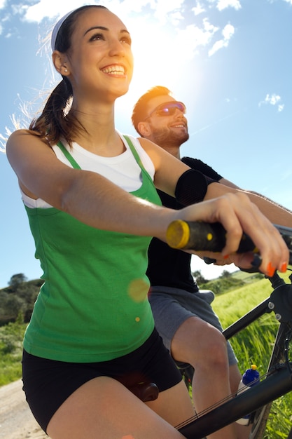 Heureux jeune couple à vélo à la campagne