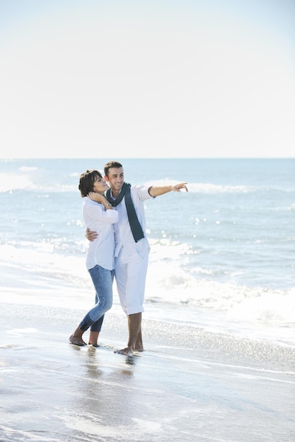 heureux jeune couple en vêtements blancs avoir des loisirs romantiques et s'amuser sur la belle plage en vacances