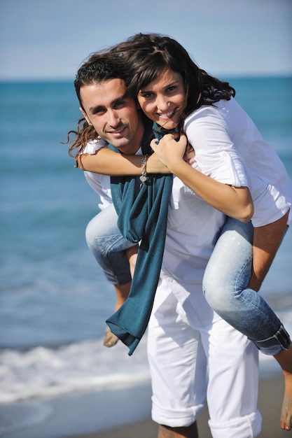 heureux jeune couple en vêtements blancs avoir des loisirs romantiques et s'amuser sur la belle plage en vacances