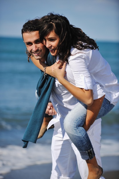 heureux jeune couple en vêtements blancs avoir des loisirs romantiques et s'amuser sur la belle plage en vacances