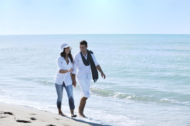 heureux jeune couple en vêtements blancs avoir des loisirs romantiques et s'amuser sur la belle plage en vacances