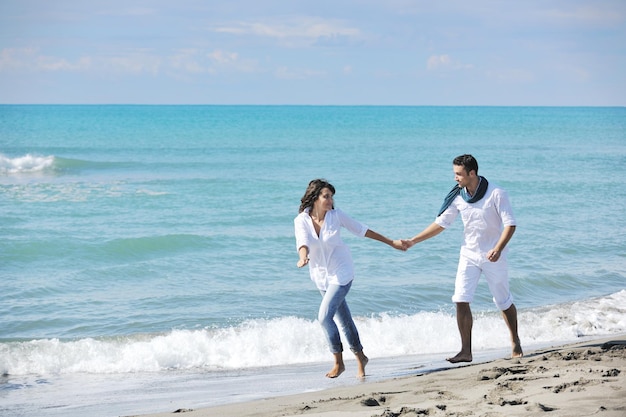 heureux jeune couple en vêtements blancs avoir des loisirs romantiques et s'amuser sur la belle plage en vacances