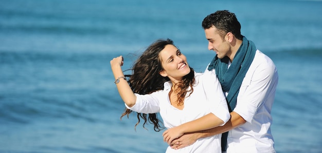 heureux jeune couple en vêtements blancs avoir des loisirs romantiques et s'amuser sur la belle plage en vacances